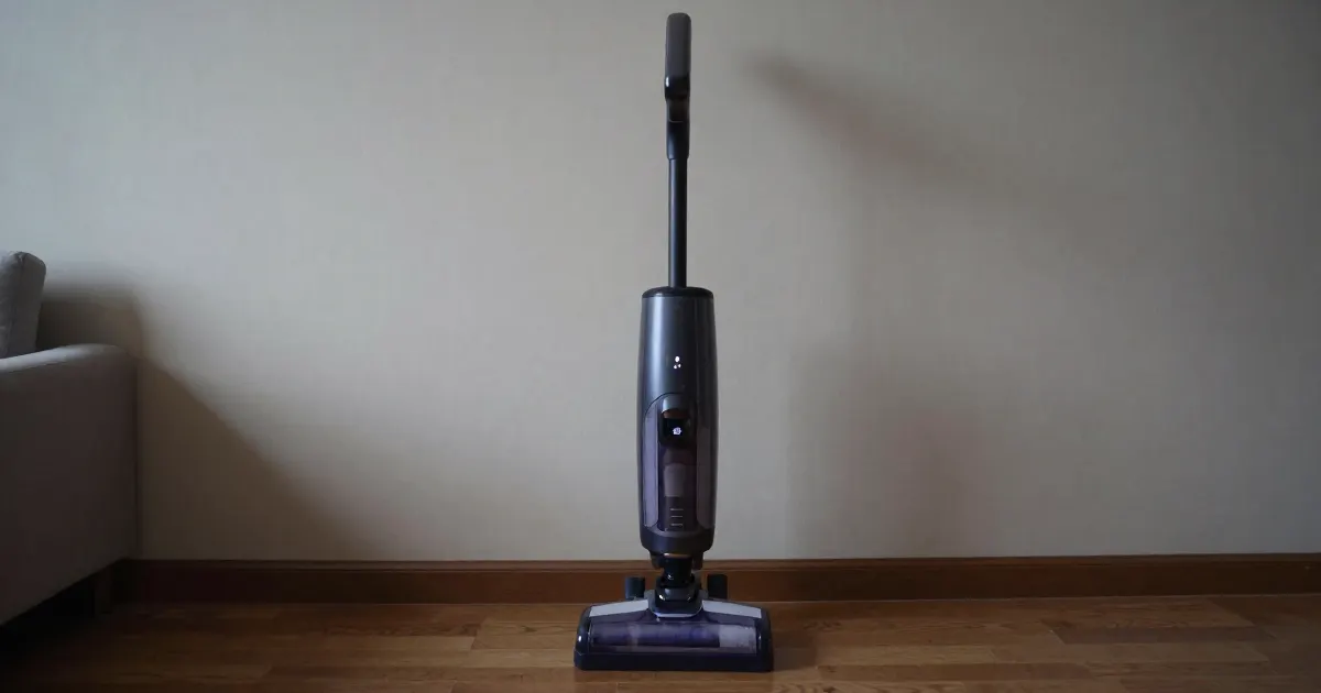 Illustration of a generic cordless stick vacuum standing upright against a wall in a living room