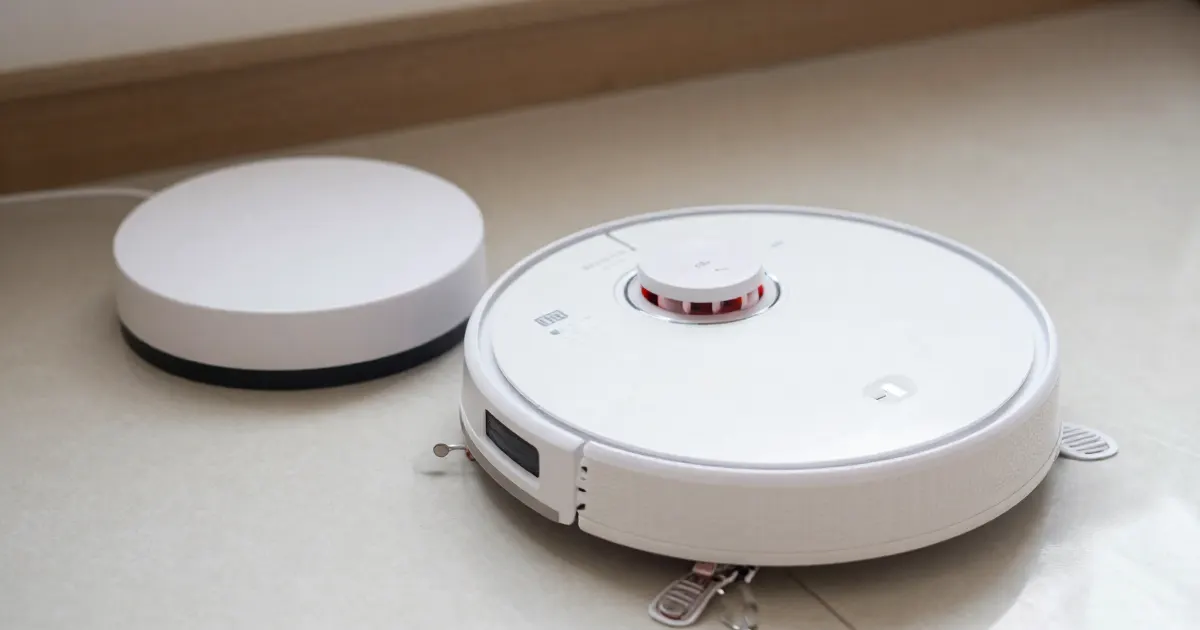Illustration of a generic white robot vacuum on a light floor beside a round white charging base