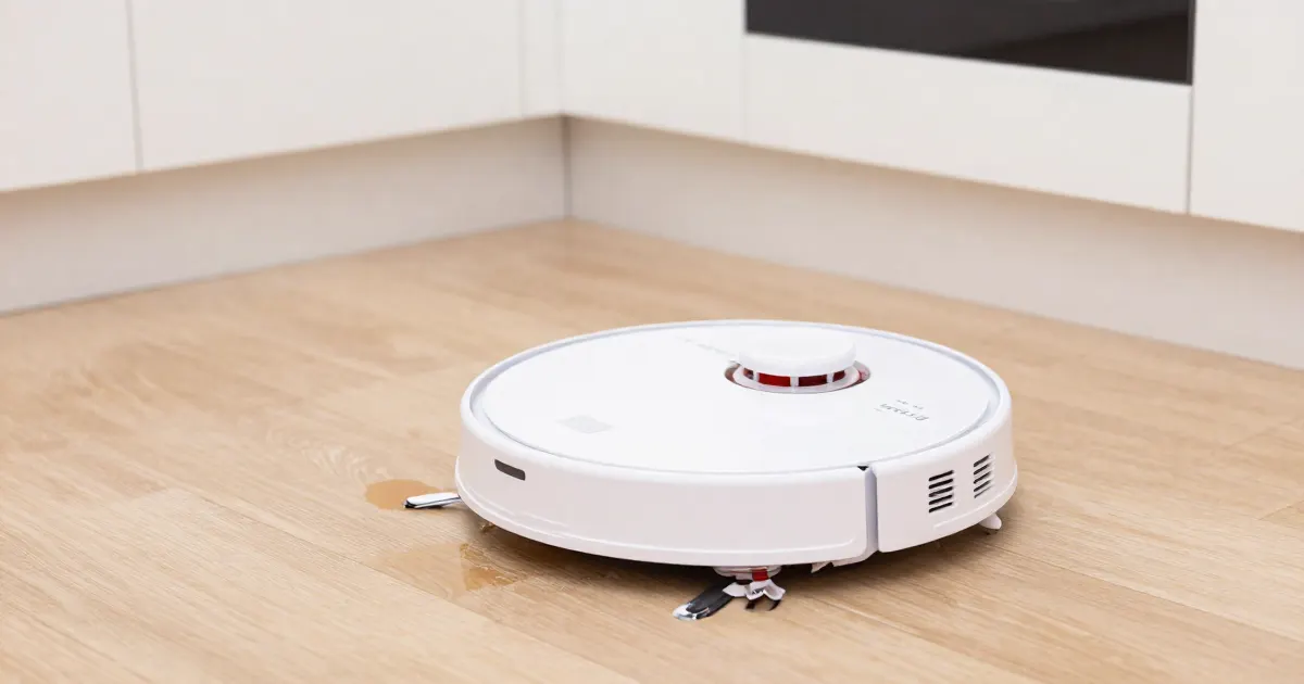 Illustration of a generic robot vacuum mop on a wooden floor with a small wet spot beside it