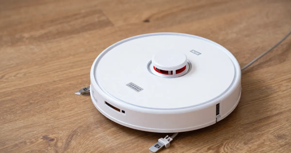 Illustration of a generic white robot vacuum on a wooden floor, seen from the front