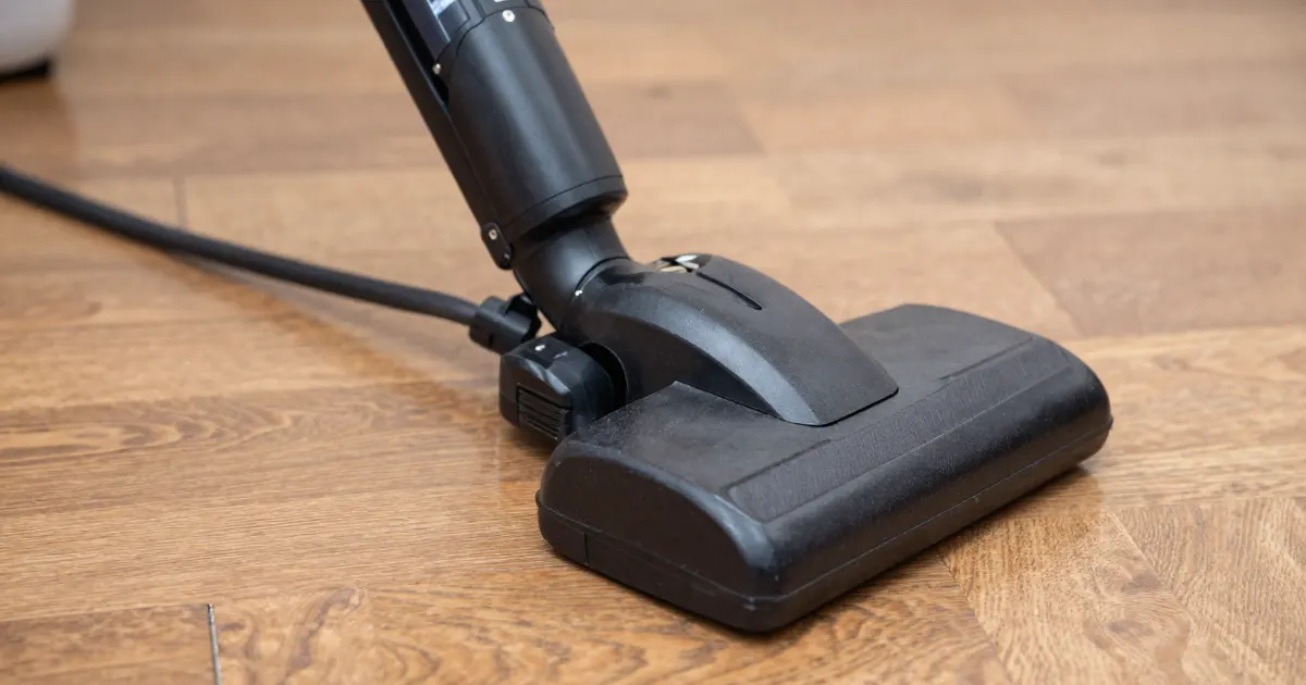 Illustration of a generic vacuum floor head on a wooden floor with its power cord trailing behind