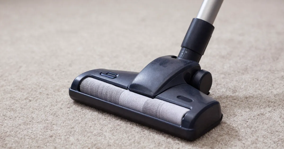 Illustration of a generic upright vacuum floor head on a beige carpet, seen close up
